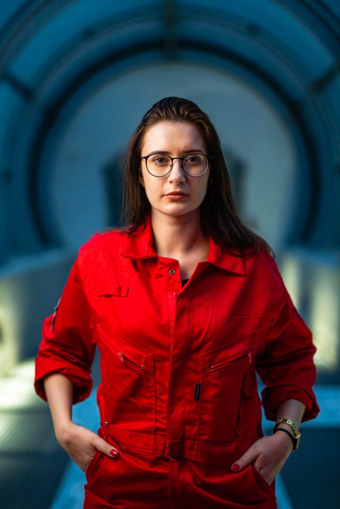 Osoba w czerwonym kombinezonie i okularach w futurystycznym tunelu.