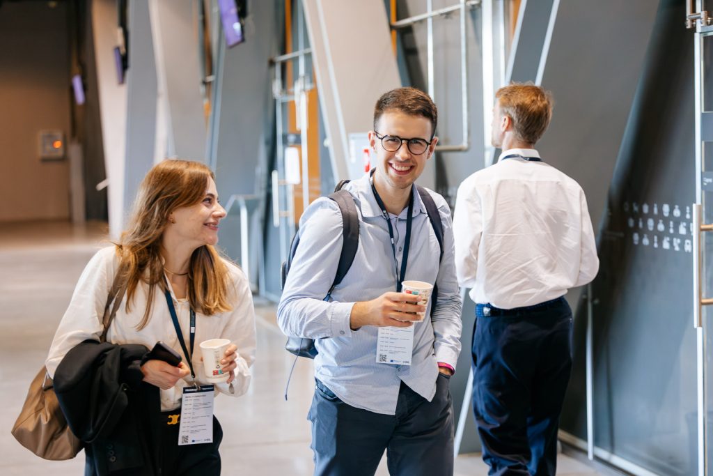 Two people talking with cups in a modern open space, likely at a business event.