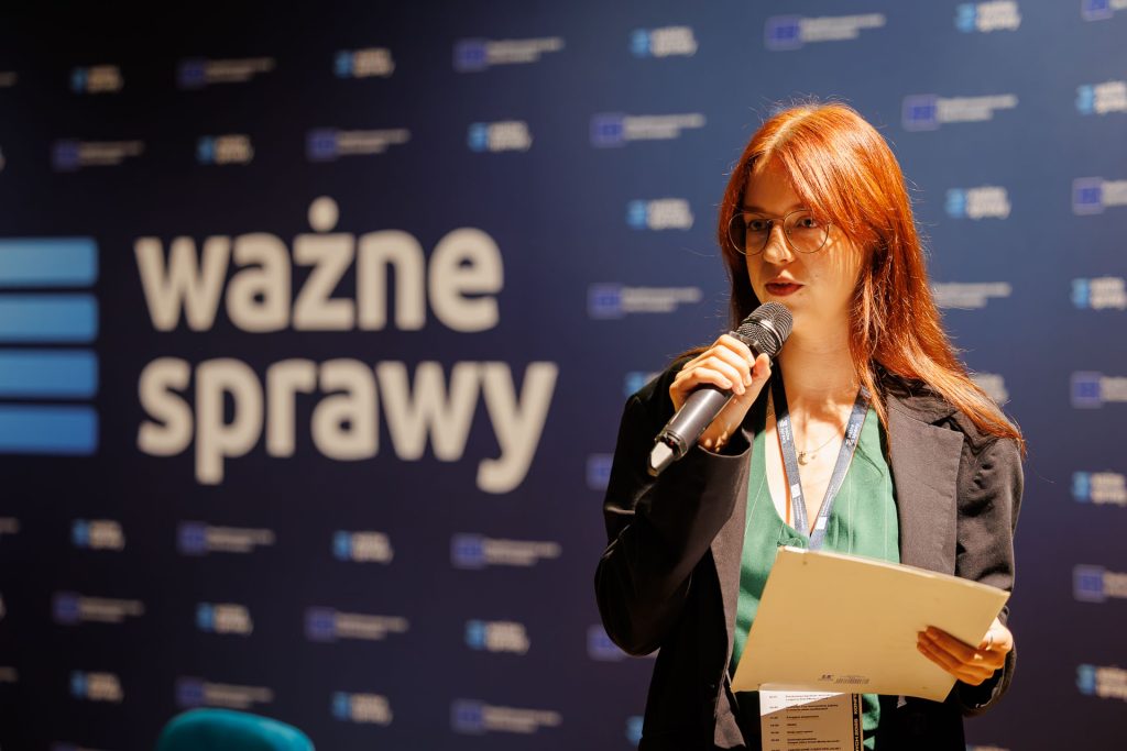 Julia Kelsz, wiceprezeska Fundacji Ważne Sprawy, z mikrofonem i notatkami na scenie konferencji Stan Młodych 2025.