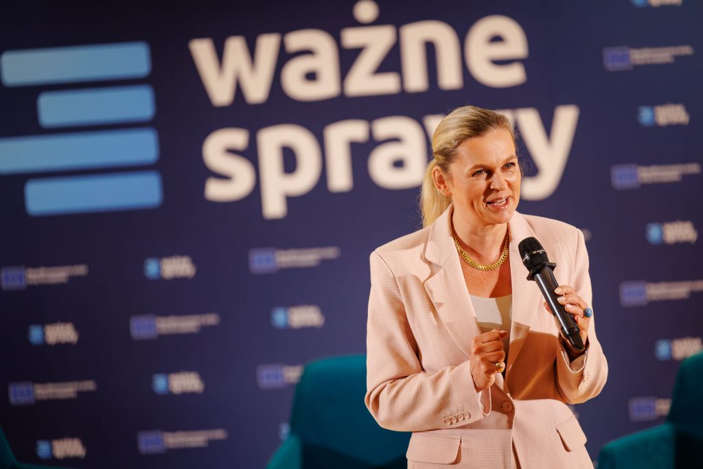 Uśmiechnięta Barbara Nowacka z mikrofonem i kartką na scenie konferencji Stan Młodych 2025.