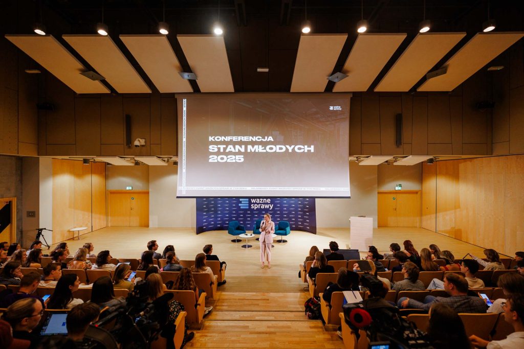Pełna sala wykładowa podczas otwarcia konferencji Stan Młodych 2025, na scenie prowadząca.