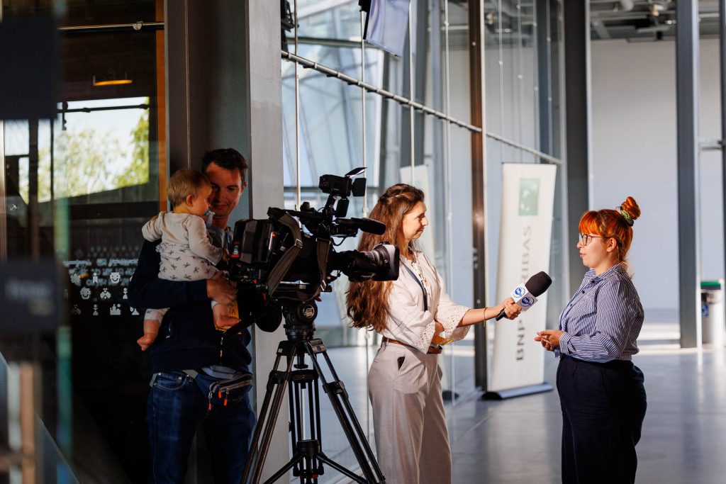 Dziennikarka z mikrofonem nagrywa wywiad z kamerzystą w holu Centrum Nauki Kopernik podczas konferencji Stan Młodych 2025.