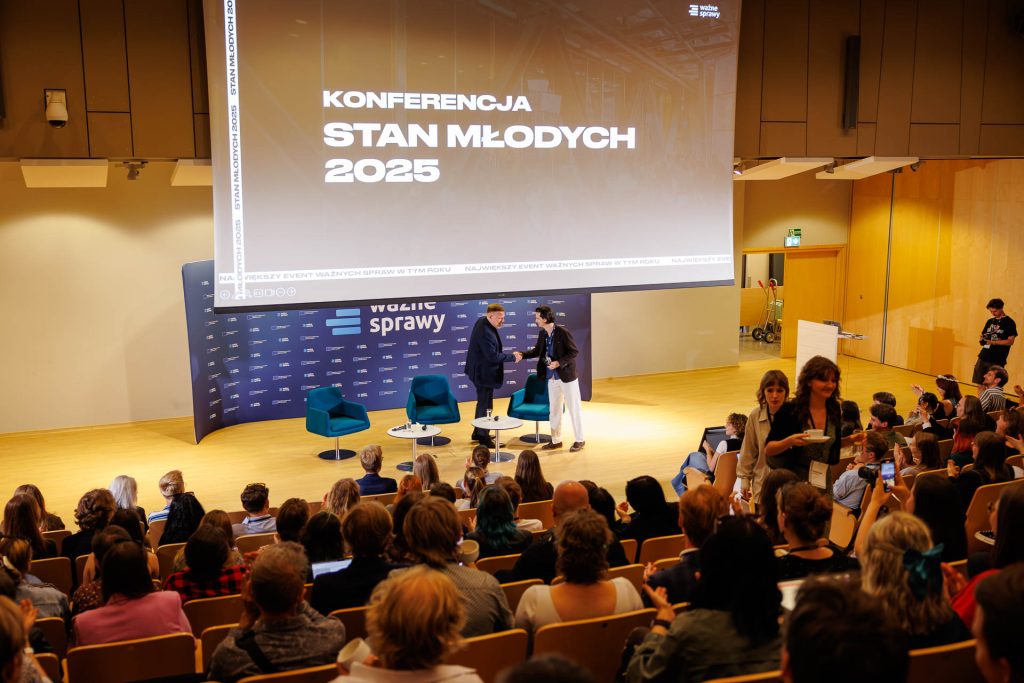 Sala konferencji Stan Młodych 2025 z nazwą wydarzenia na ekranie i prowadzącymi na scenie.