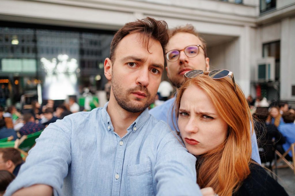Troje uczestników robi selfie z udawanymi poważnymi minami, w tle tłum – konferencja Stan Młodych 2025.