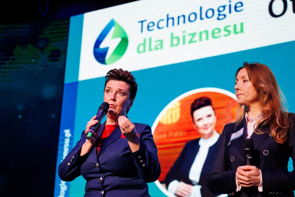 Dwie prowadzące z mikrofonami na scenie konferencji Technologie dla Biznesu.