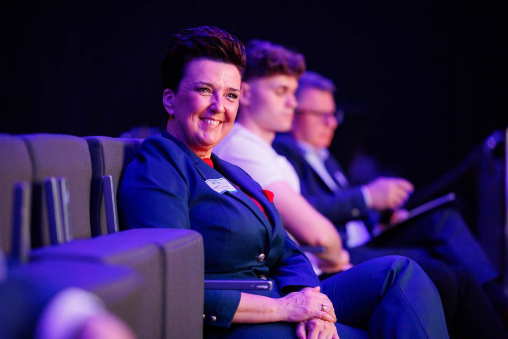 Uśmiechnięta panelistka siedzi w fotelu na scenie podczas dyskusji na Technologie dla Biznesu.