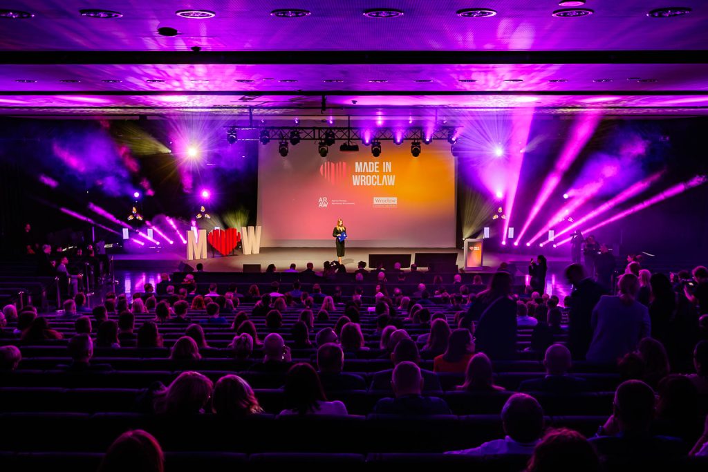Sala Made in Wrocław 2025 w fioletowym świetle, publiczność przed sceną z ekranem.