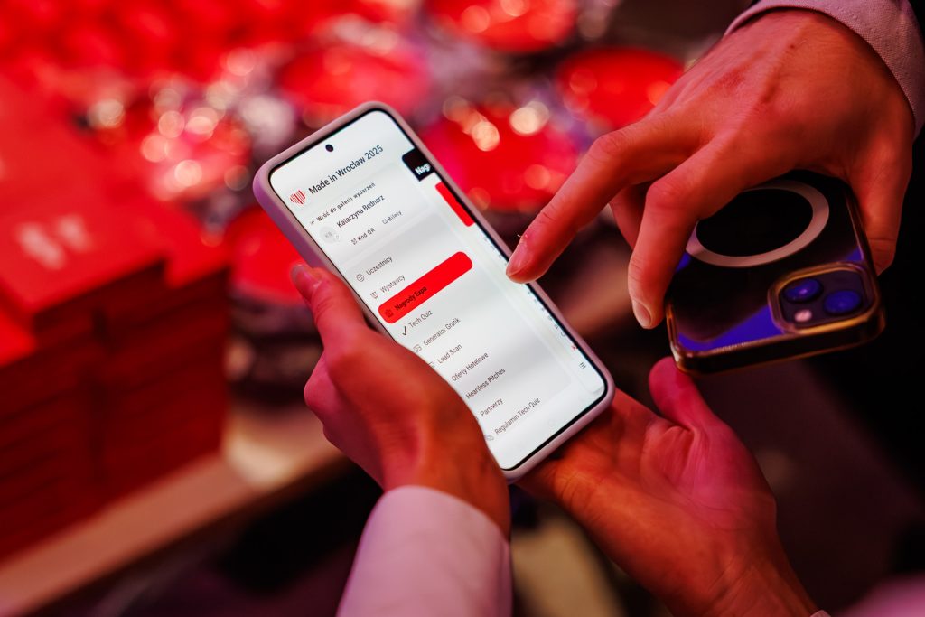 Dłonie trzymające telefon z otwartą aplikacją wydarzenia Made in Wrocław 2025.