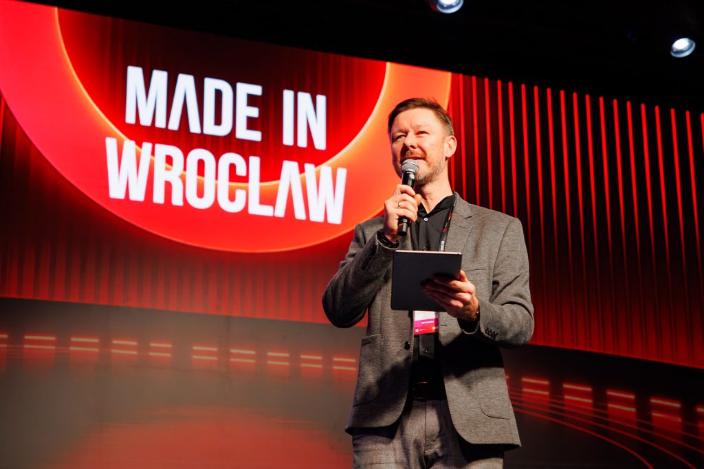 Prowadzący z mikrofonem i tabletem na scenie Made in Wrocław 2025.