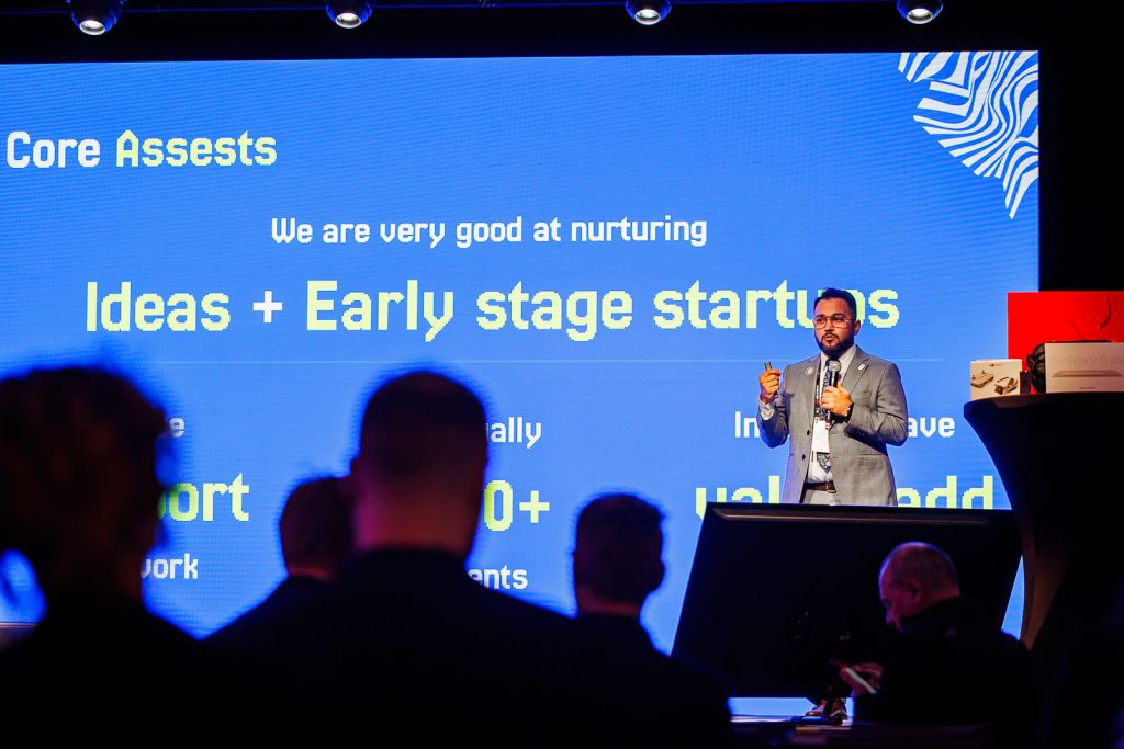 Prelegent na scenie przed ekranem z prezentacją o wspieraniu startupów na Made in Wrocław 2025.